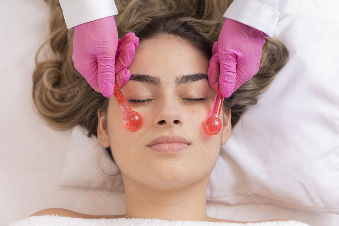 mulher deitada em maca em clinica de estética procedimento de massagem e relaxamento facial