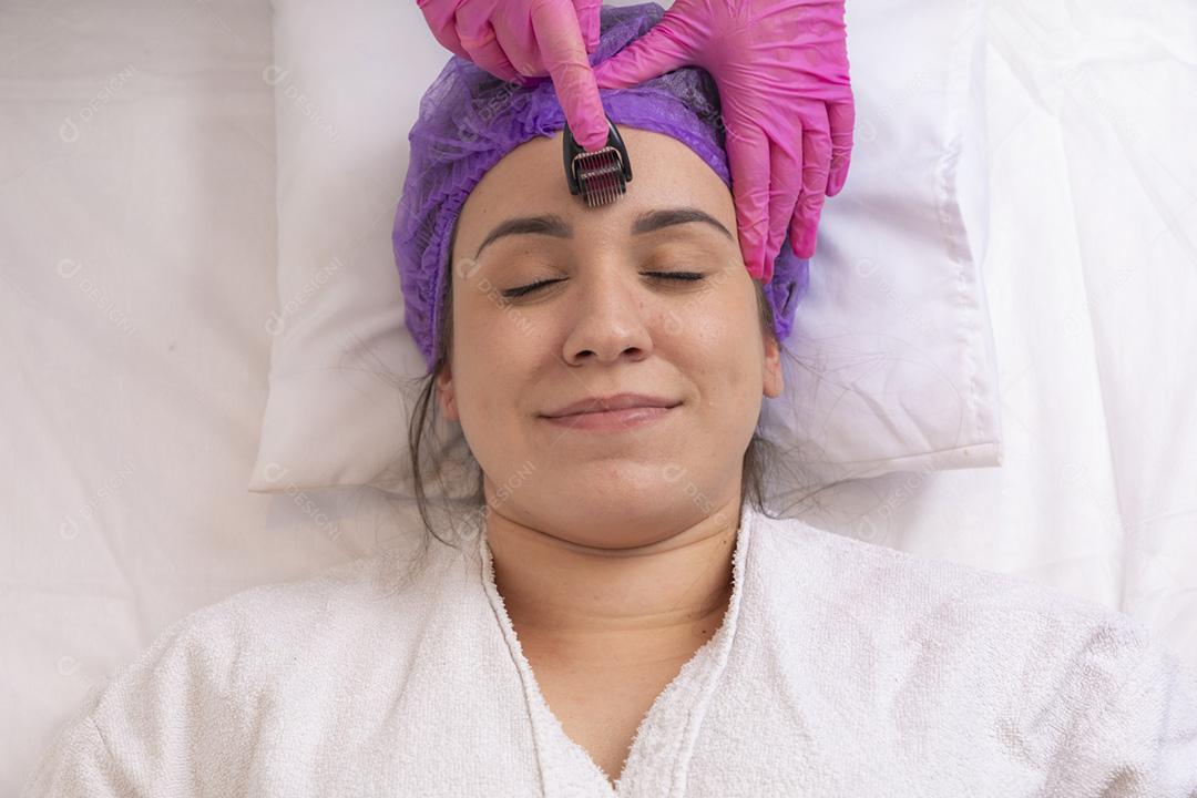 Rosto feminino de close-up com dermaroller para procedimentos de mesoterapia