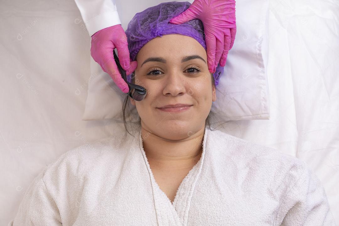 Rosto feminino de close-up com dermaroller para procedimentos de mesoterapia