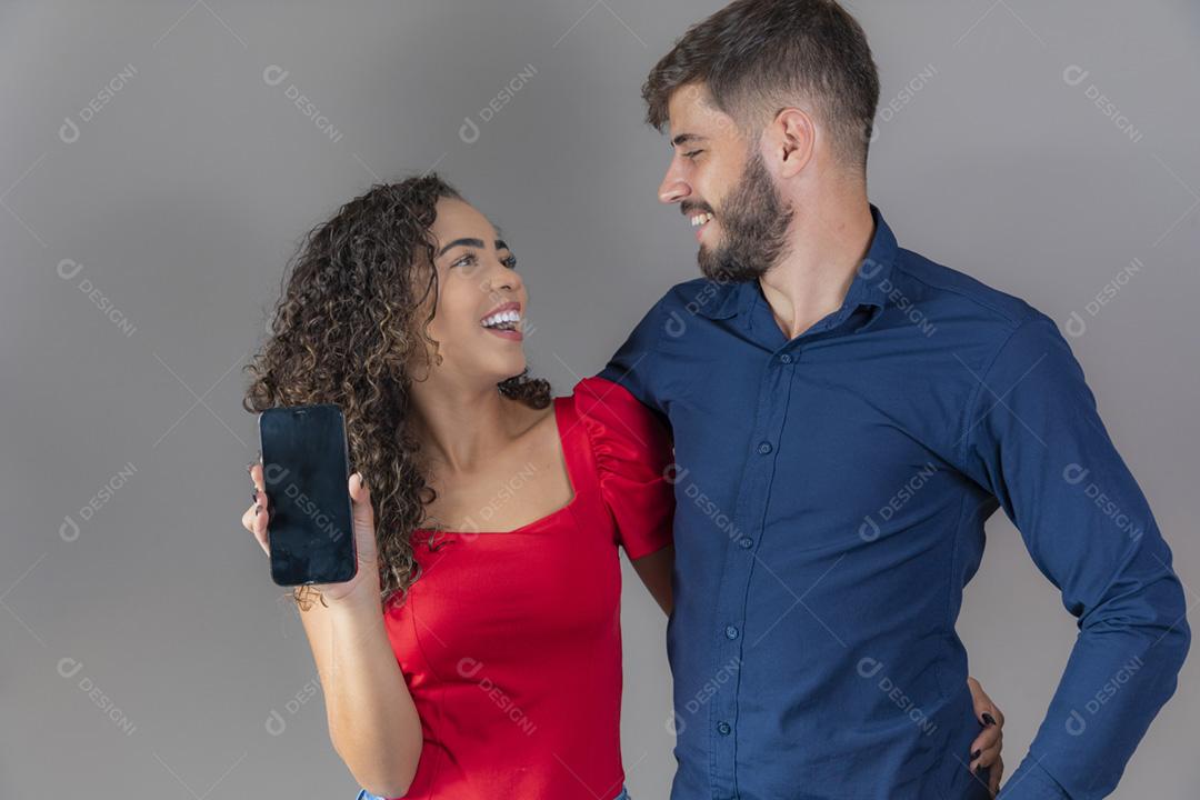 Casal de namorados segurando um smartphone com a tela com espaço