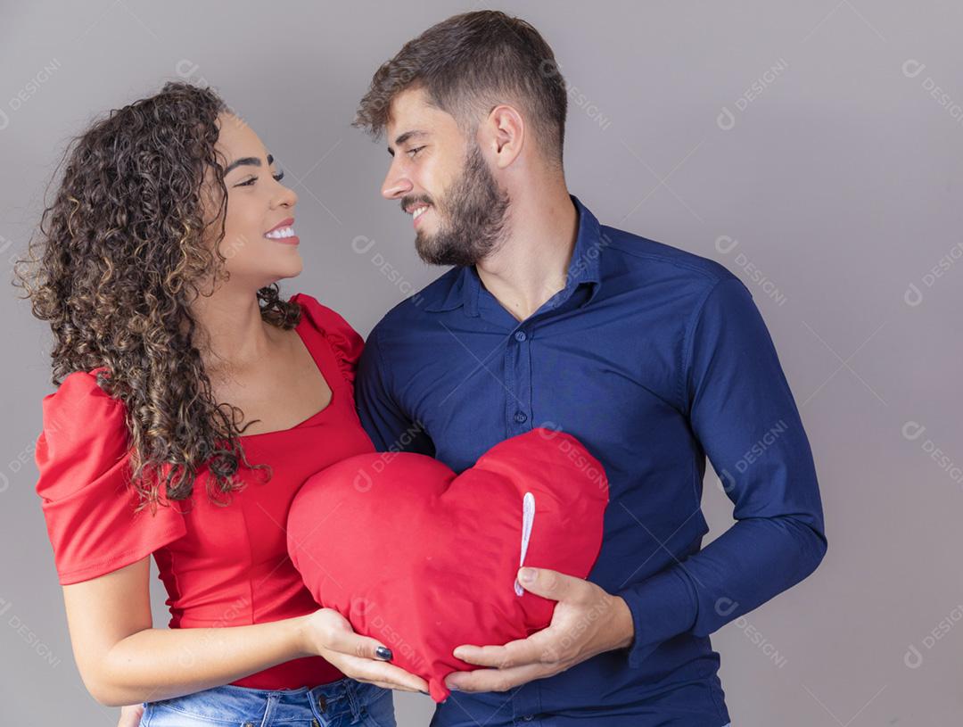 casal jovem apaixonado segurando um coração de pelúcia