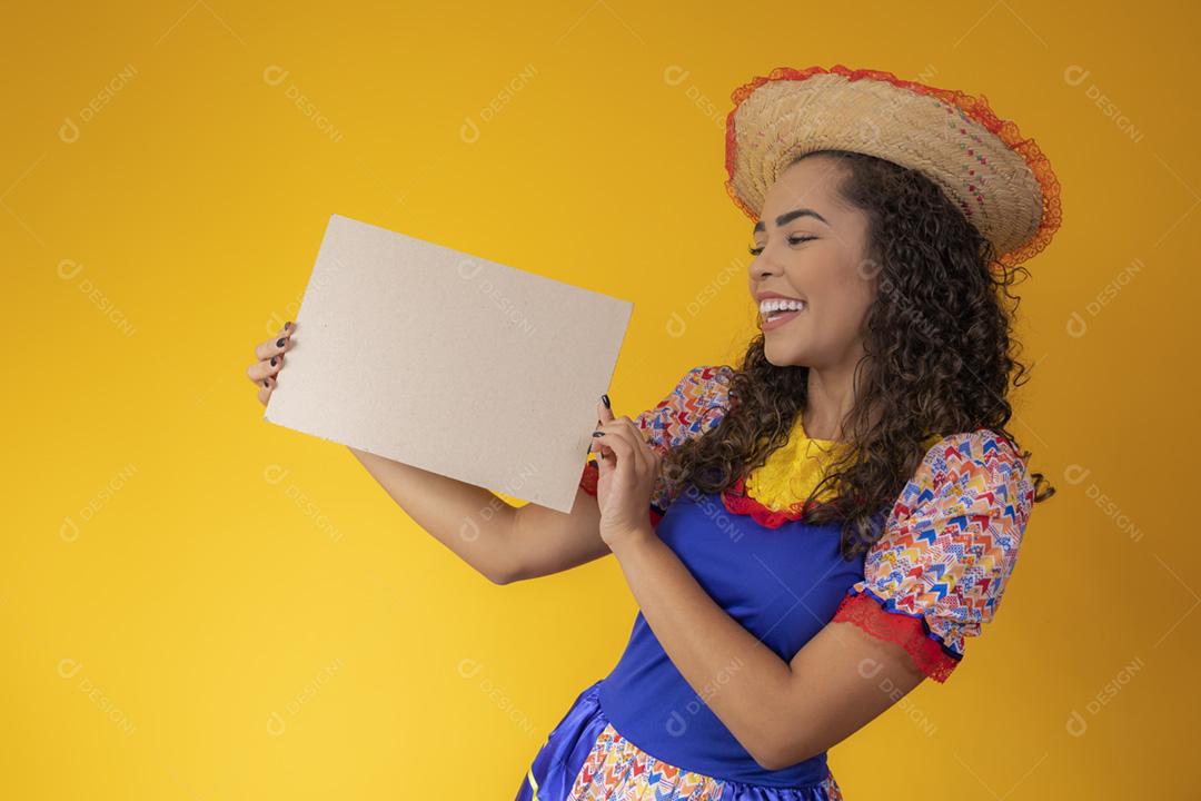 Linda mulher vestida com roupa de festa junina segurando um s em branco