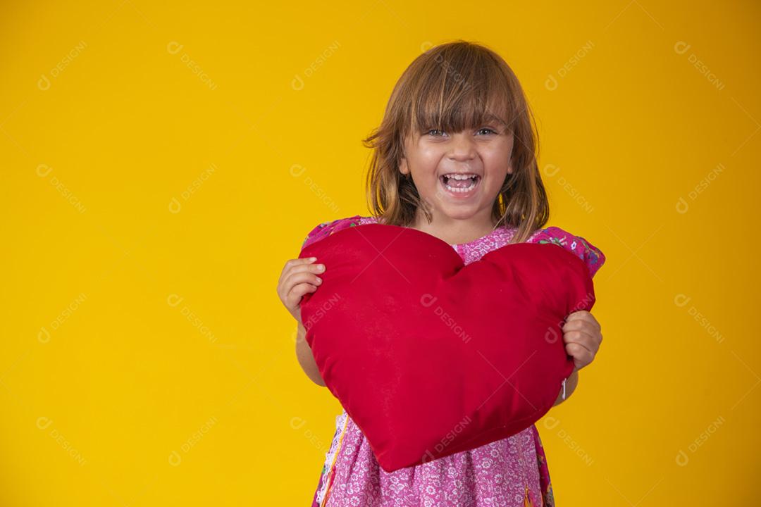 Menina caucasiana bonitinha segurando um coração de pelúcia vermelho. Sentimentos,