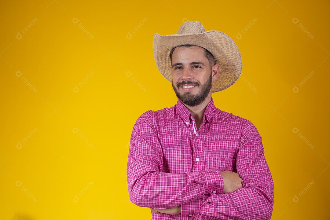 Jovem agricultor com camisa xadrez e braços cruzados em backgro amarelo