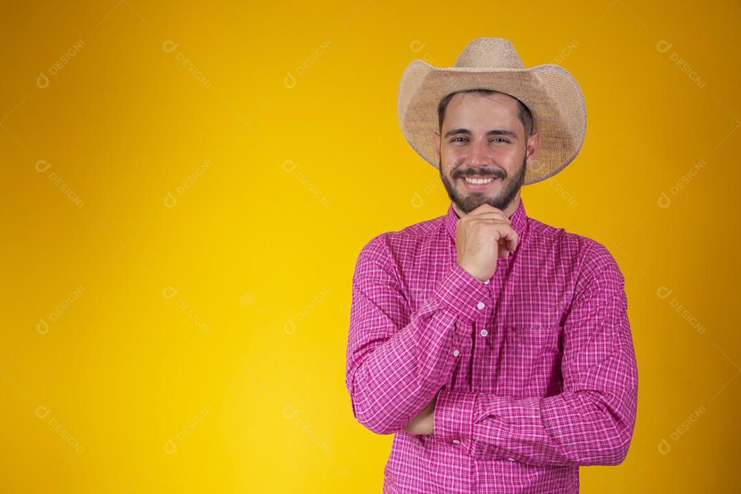 jovem agricultor sorrindo com a mao no queixo olhando para a câmera no fundo amarelo