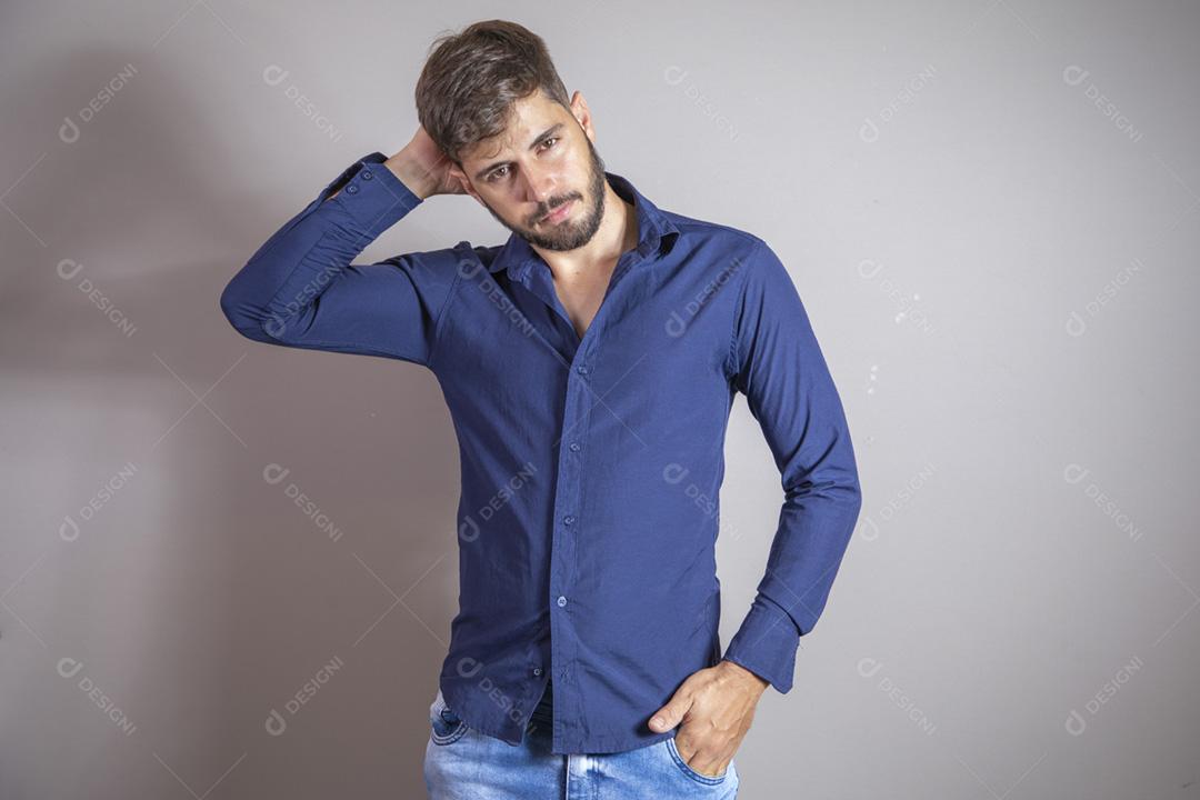 jovem com a mao no cabelo olhando para a câmera no fundo cinza