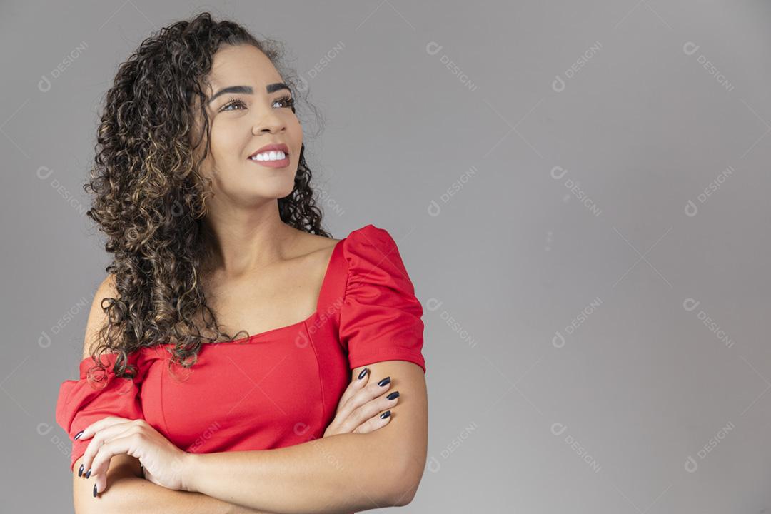 Retrato de uma mulher afro-americana sorridente em pé com os braços cr