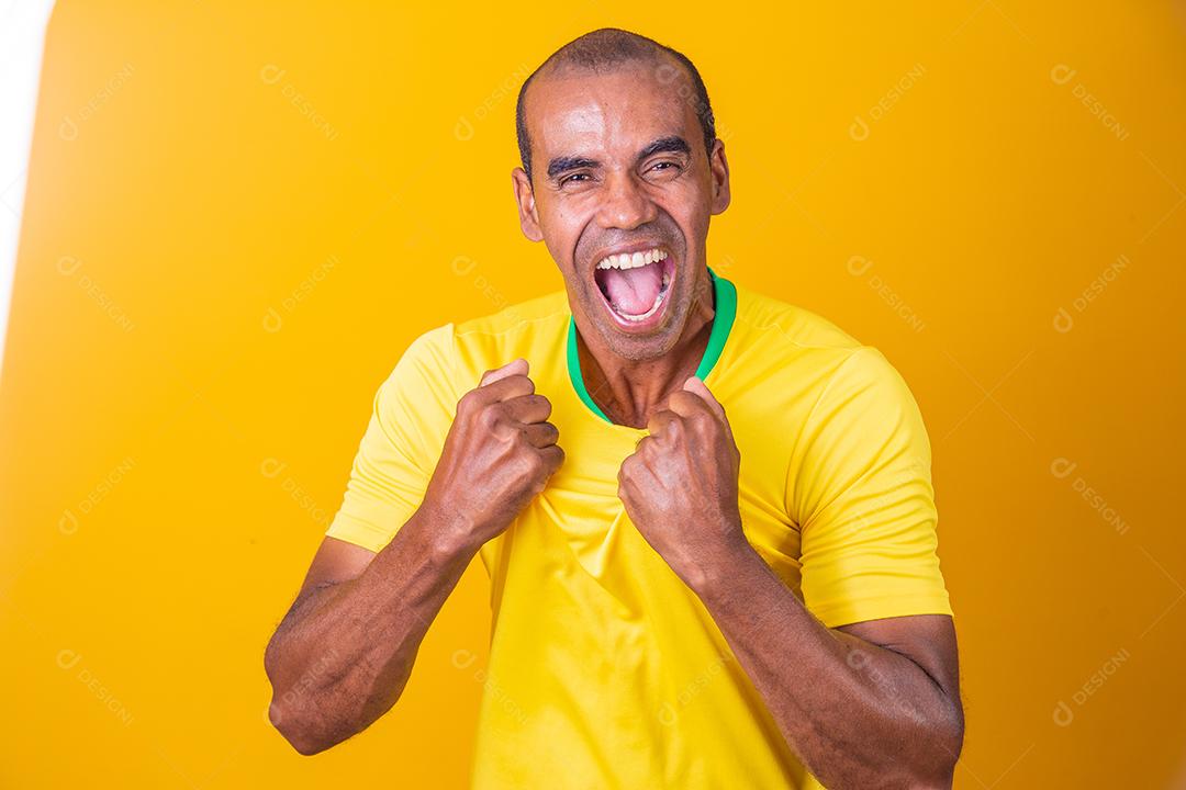 homem afro brasileiro bonito, fã brasileiro, brasil, copa do mundo 2022, punhos cerrados, gritando, torcendo, vibrando, gol.