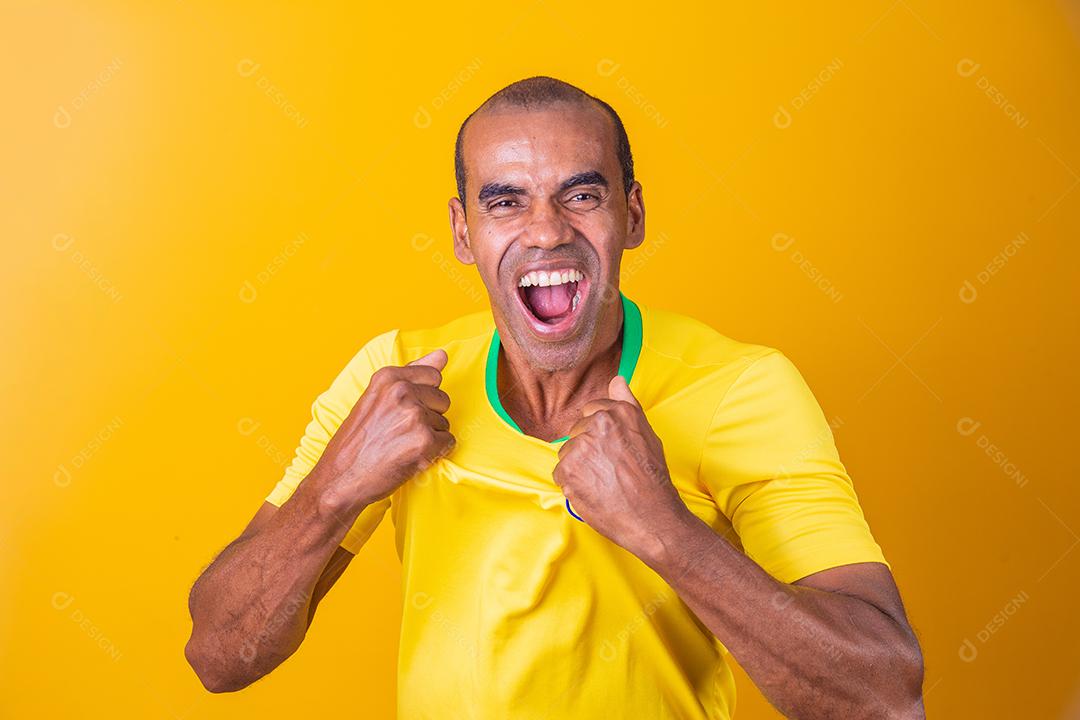 homem afro brasileiro bonito, fã brasileiro, brasil, copa do mundo 2022, punhos cerrados, gritando, torcendo, vibrando, gol.