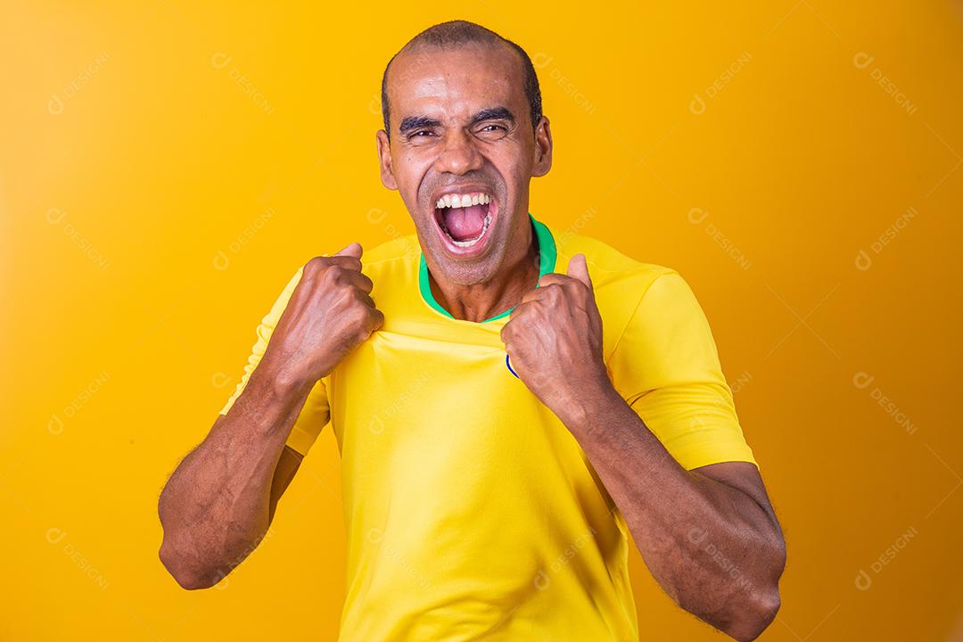 homem afro brasileiro bonito, fã brasileiro, brasil, copa do mundo 2022, punhos cerrados, gritando, torcendo, vibrando, gol.