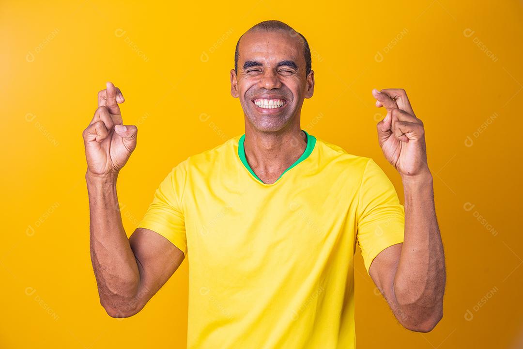 Jogador de futebol brasileiro com os dedos cruzados desejando sorte