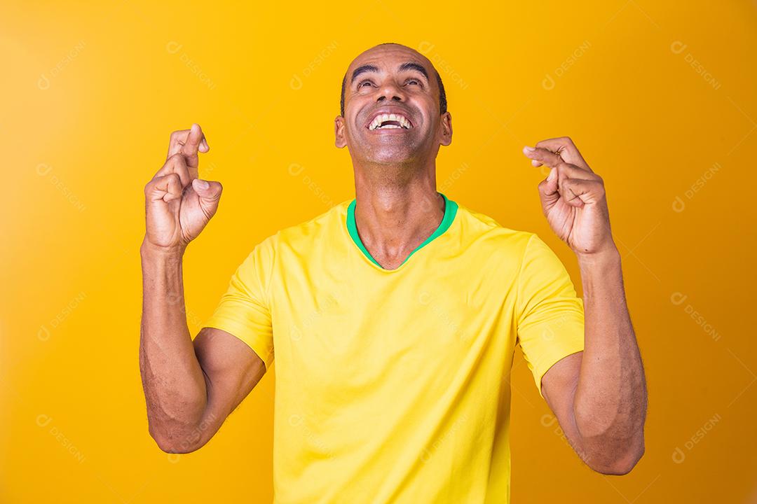 Jogador de futebol brasileiro com os dedos cruzados desejando sorte