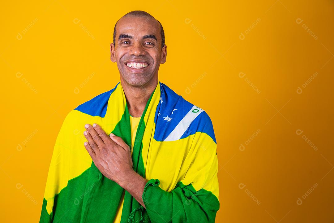 homem afro brasileiro bonito. Fã brasileiro. Copa do Mundo 2022, mão no peito cantando o hino nacional. Música brasileira. amada pátria. patriota.