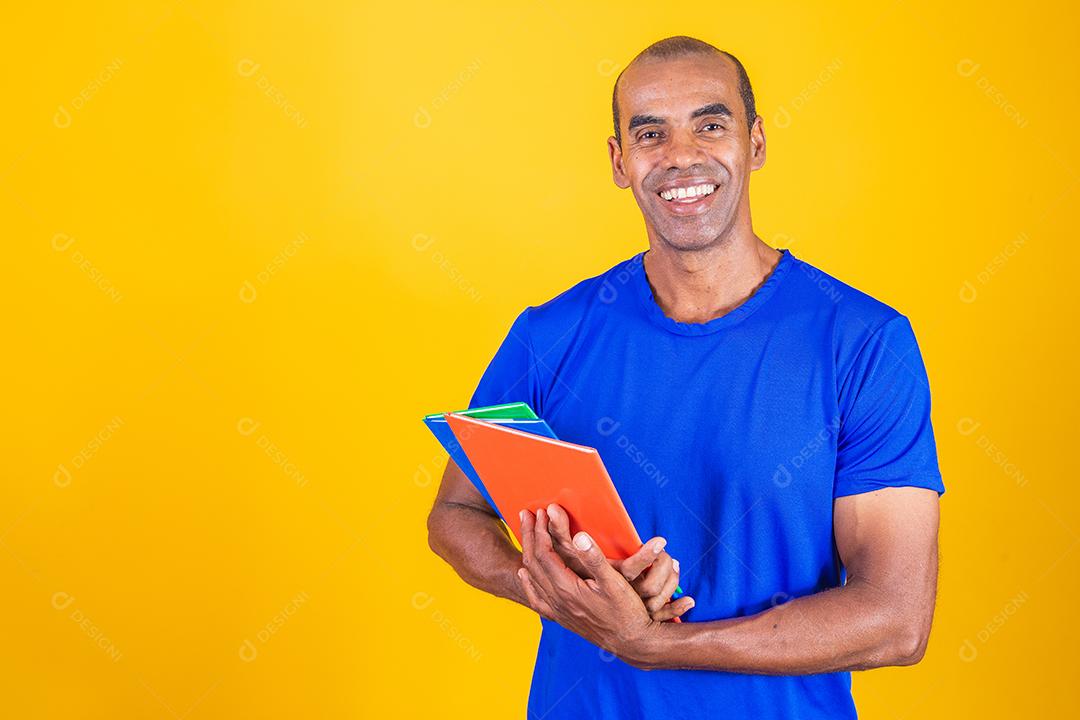 Homem estudante maduro sorrindo olhando para a câmera em fundo amarelo