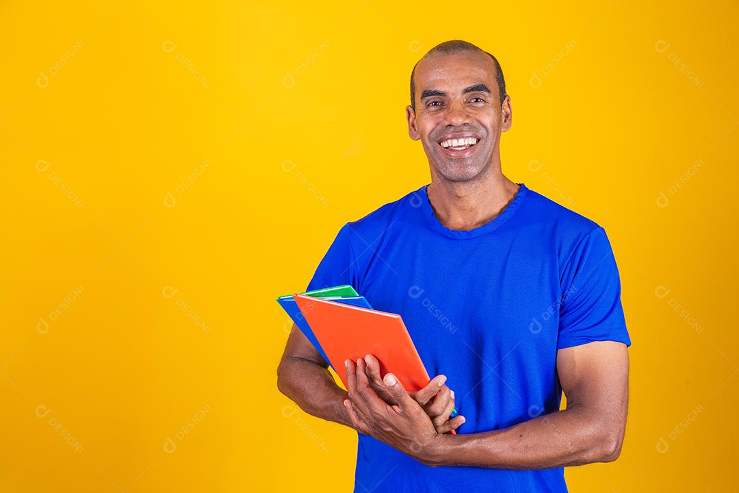 Homem estudante maduro sorrindo olhando para a câmera com espaço de cópia em fundo amarelo