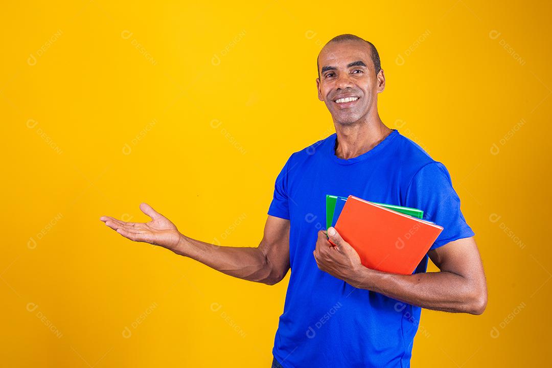 Homem estudante maduro com notebooks nos braços apontando para o lado