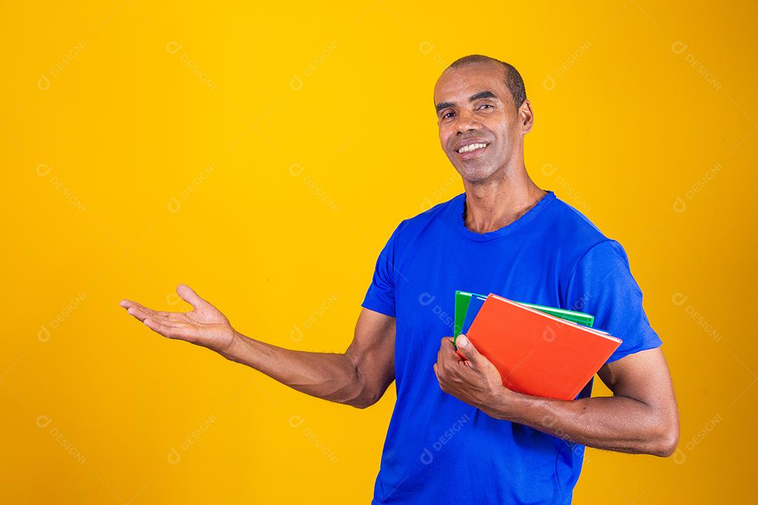 Homem estudante maduro com notebooks nos braços apontando para o lado