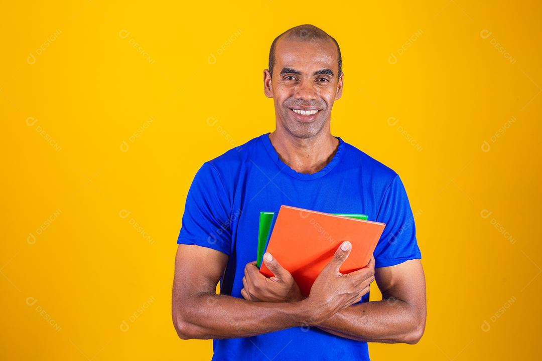 Homem estudante maduro sorrindo olhando para a câmera em fundo amarelo. homem estudante negro maduro