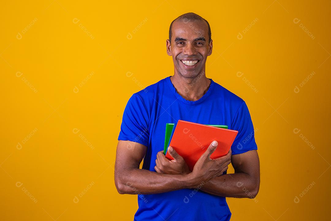 Homem estudante maduro sorrindo olhando para a câmera em fundo amarelo. homem estudante negro maduro