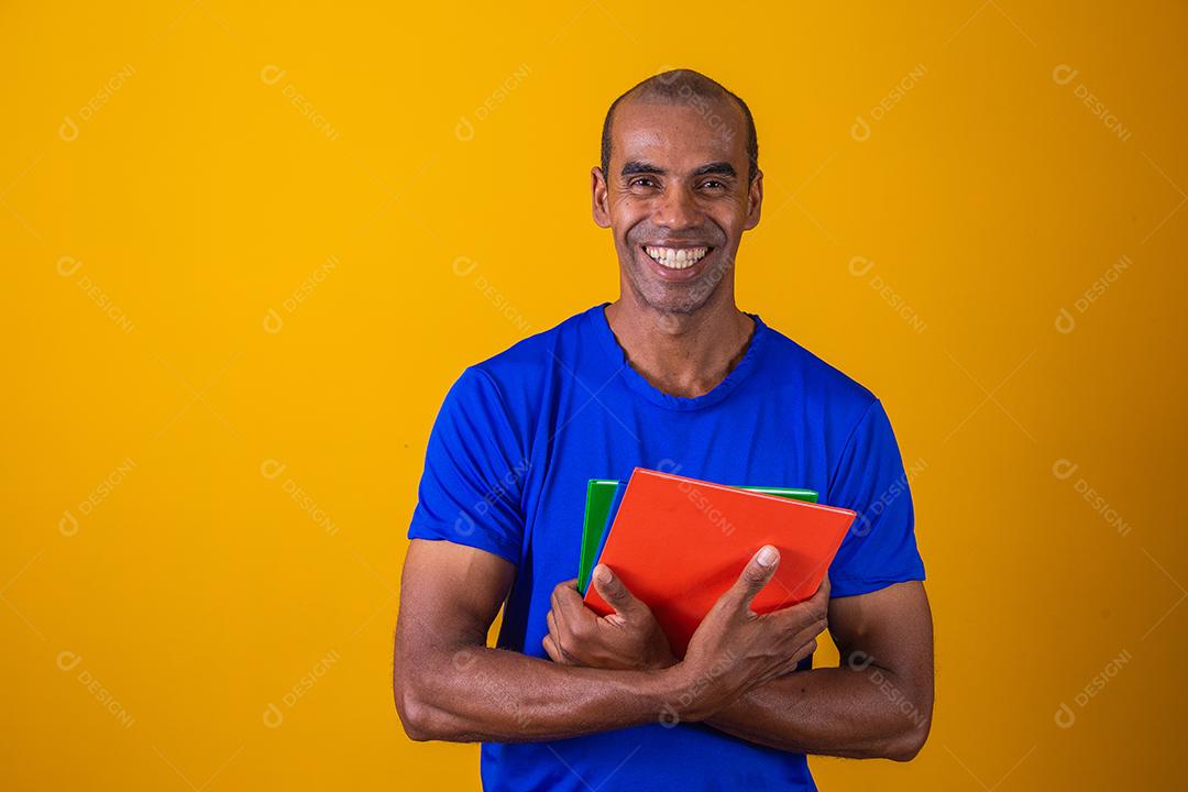 Homem estudante maduro sorrindo olhando para a câmera em fundo amarelo. homem estudante negro maduro