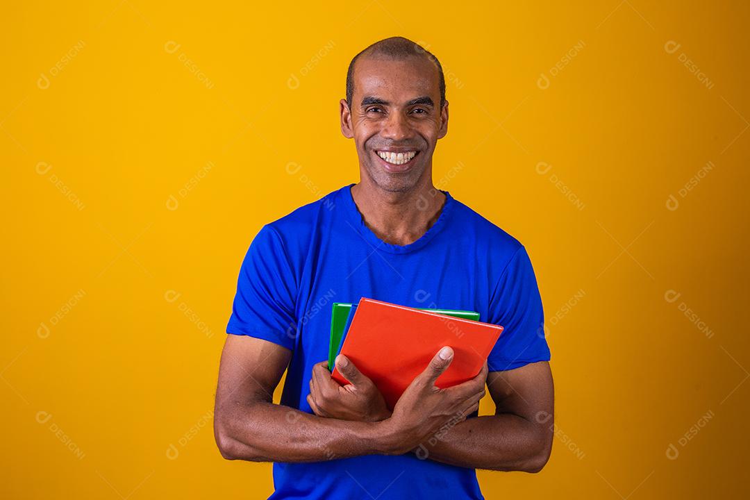 Homem estudante maduro sorrindo olhando para a câmera em fundo amarelo. homem estudante negro maduro