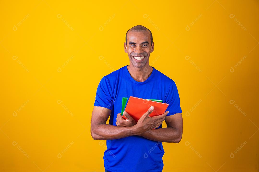 Homem estudante maduro sorrindo olhando para a câmera em fundo amarelo. homem estudante negro maduro