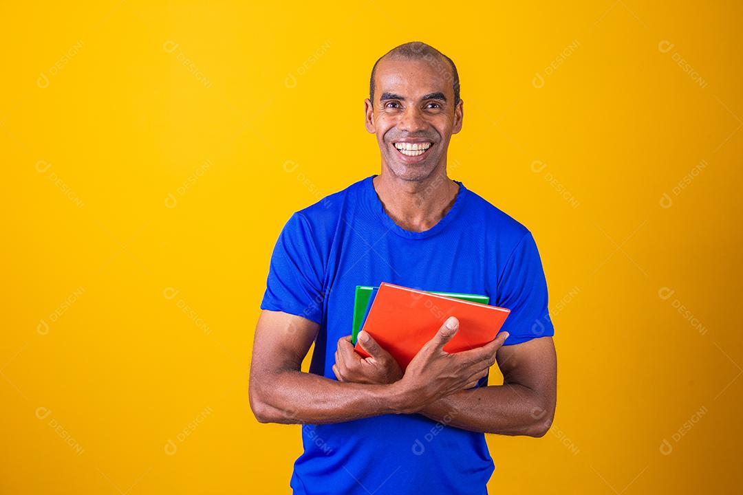 Homem estudante maduro sorrindo olhando para a câmera em fundo amarelo. homem estudante negro maduro