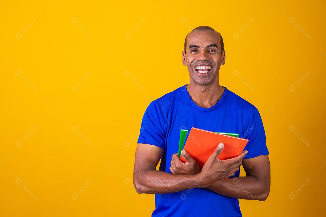 Homem estudante maduro sorrindo olhando para a câmera em fundo amarelo. homem estudante negro maduro