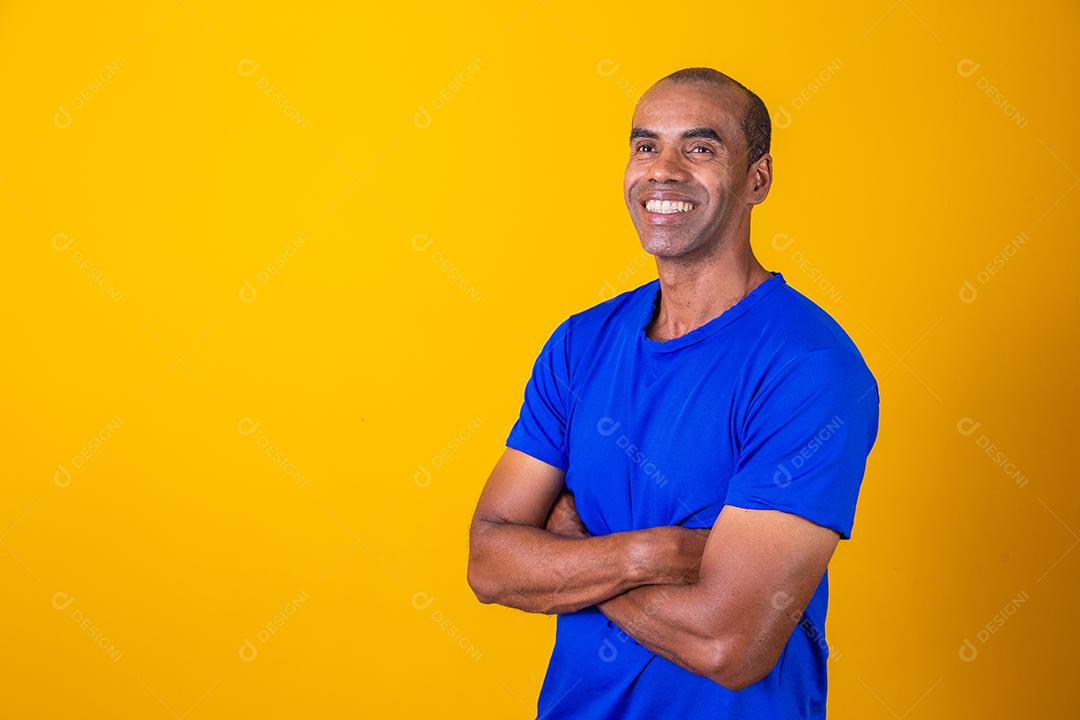 Homem negro mais velho cruzando os braços com confiança. otimista, feliz. Feliz. Homem afro com braços cruzados em fundo amarelo