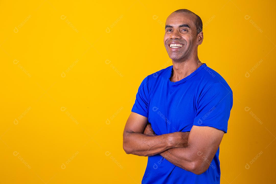 Homem negro mais velho cruzando os braços com confiança. otimista, feliz. Feliz. Homem afro com braços cruzados em fundo amarelo