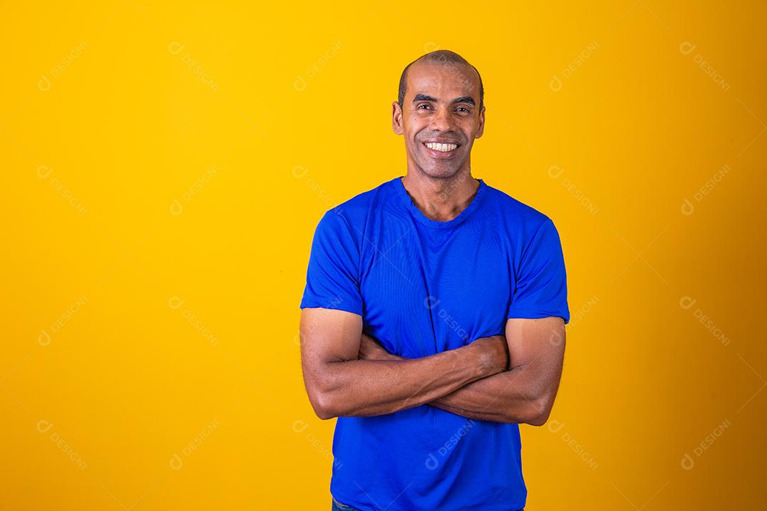 Homem negro mais velho cruzando os braços com confiança. otimista, feliz. Feliz. Homem afro com braços cruzados em fundo amarelo