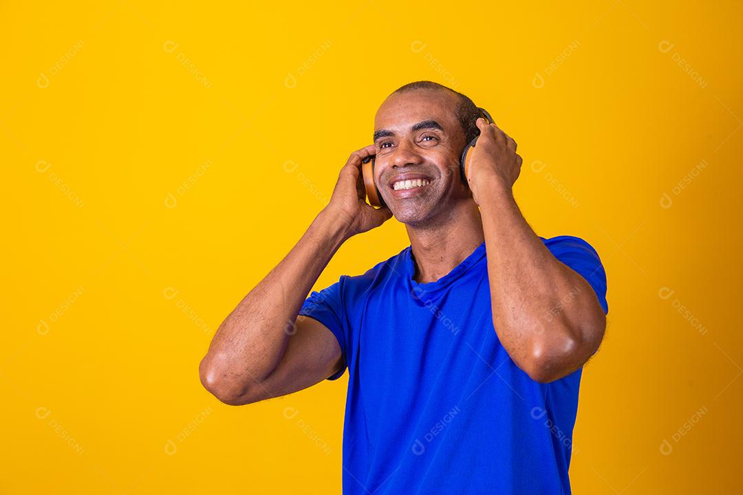 Homem Africano feliz sorrindo ouvindo música em fones de ouvido.