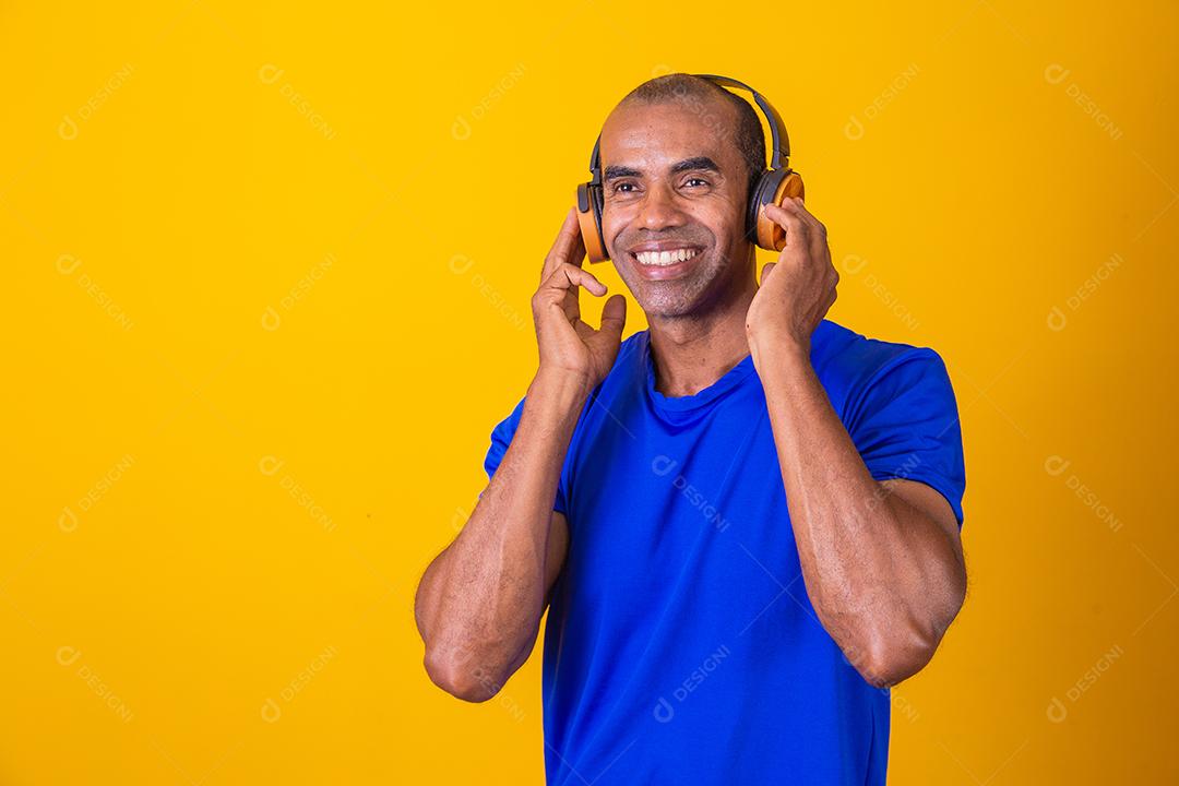 Homem Africano feliz sorrindo ouvindo música em fones de ouvido.