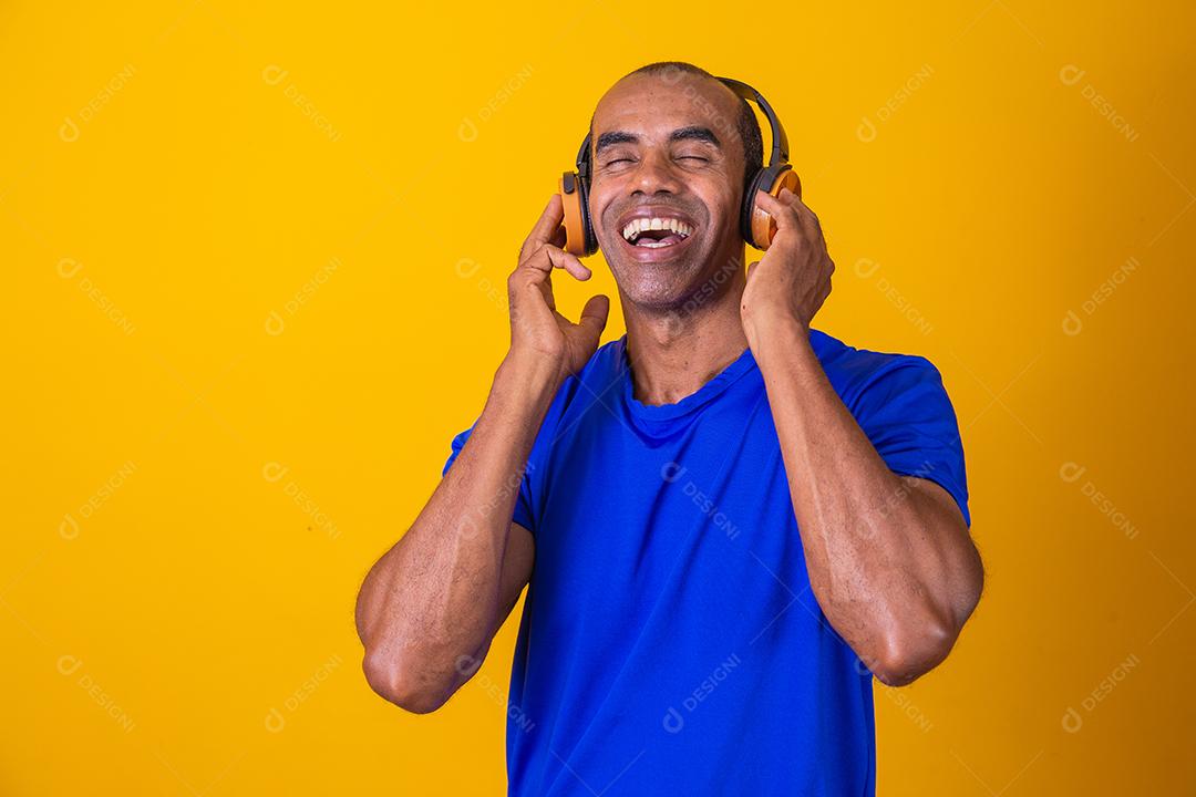 Homem Africano feliz sorrindo ouvindo música em fones de ouvido.