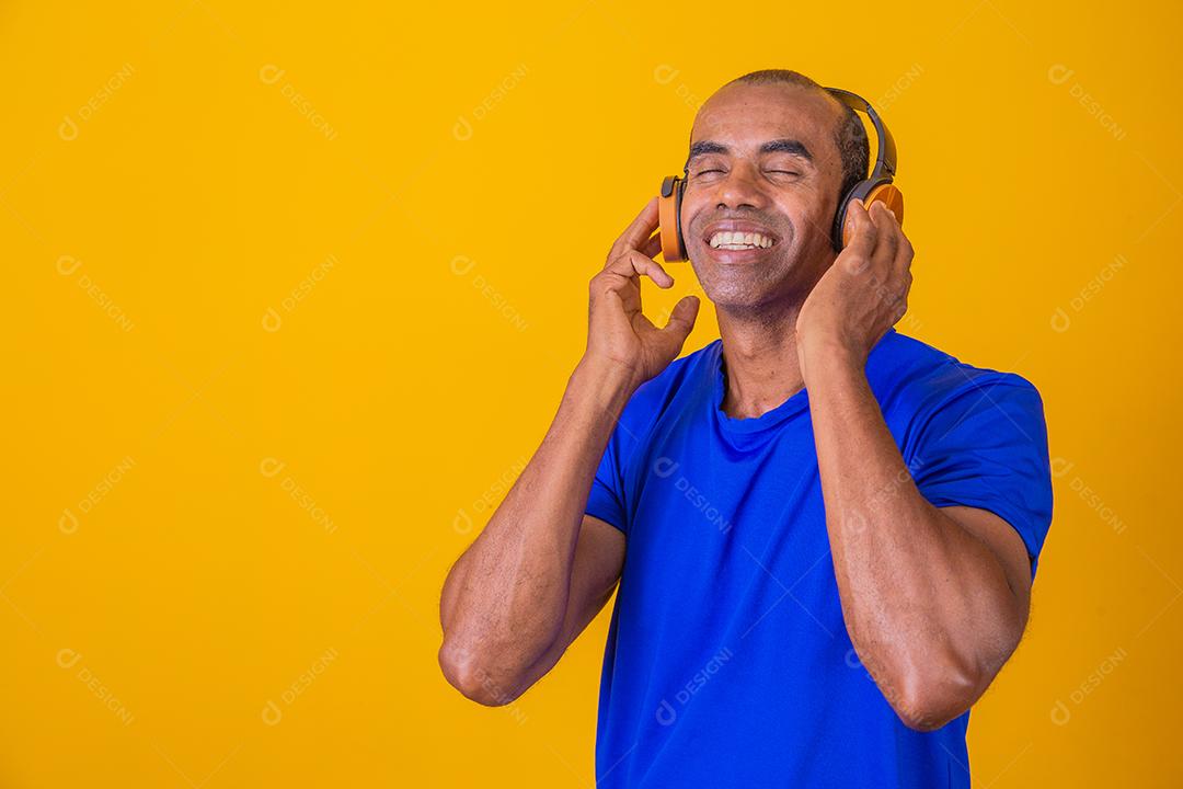 Homem Africano feliz sorrindo ouvindo música em fones de ouvido.