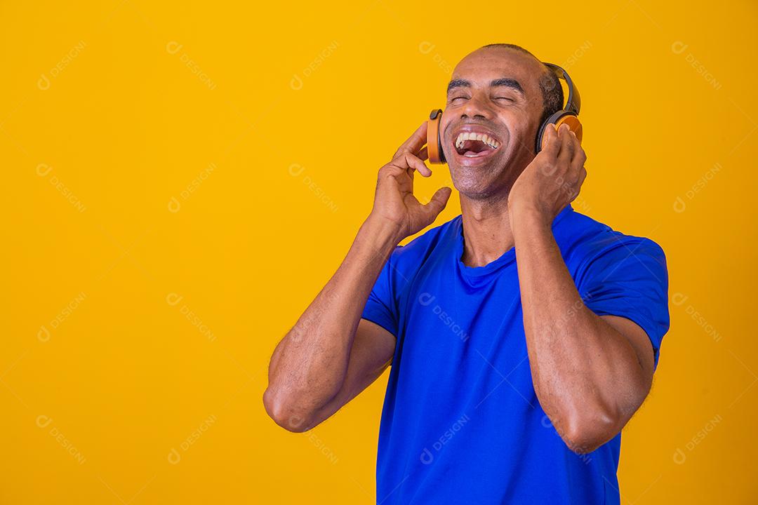 Homem Africano feliz sorrindo ouvindo música em fones de ouvido.