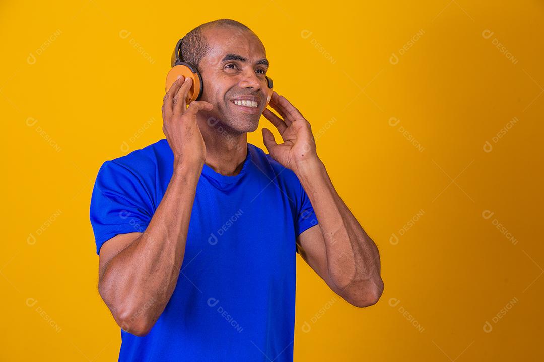 Homem Africano feliz sorrindo ouvindo música em fones de ouvido.