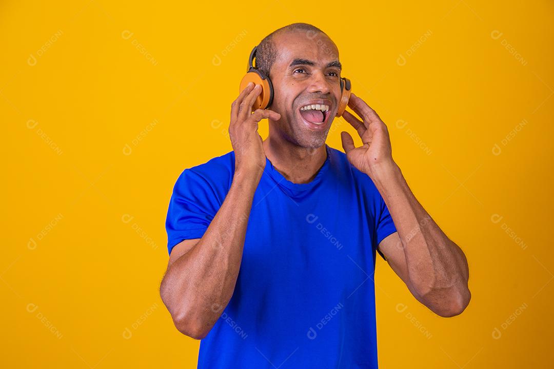 Homem Africano feliz sorrindo ouvindo música em fones de ouvido.