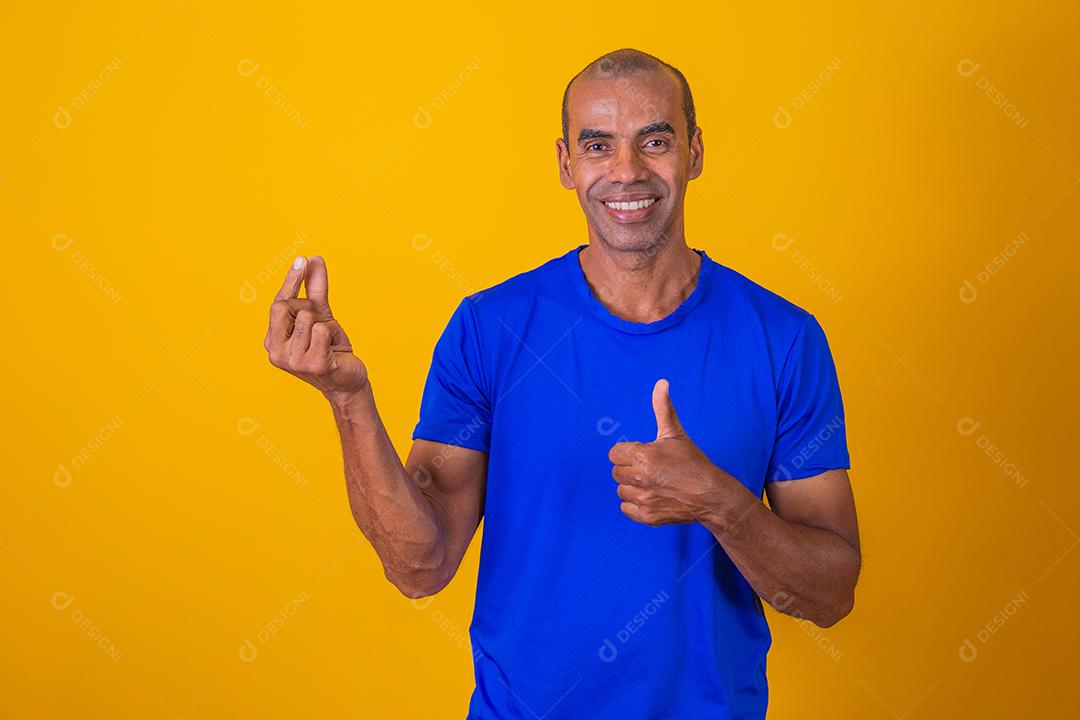 Homem afro fingindo segurar algo com uma mão e aprovando com a outra com o polegar para cima