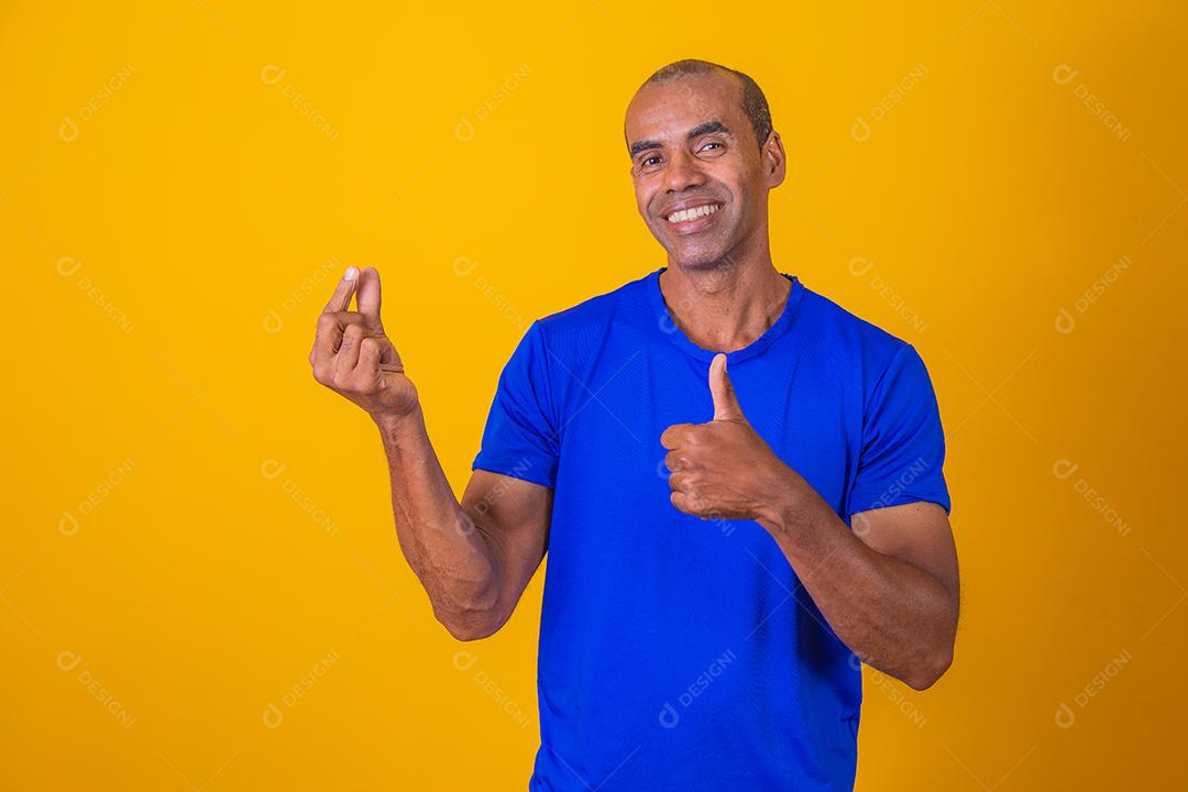 Homem afro fingindo segurar algo com uma mão e aprovando com a outra com o polegar para cima