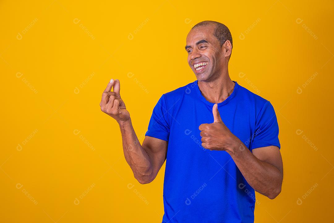 Homem afro fingindo segurar algo com uma mão e aprovando com a outra com o polegar para cima