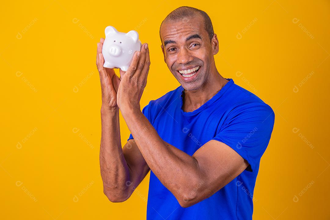 Homem afro segurando um cofrinho