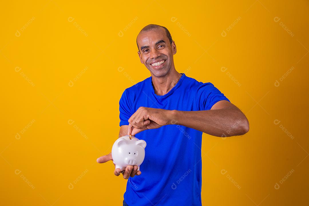 Homem afro segurando um cofrinho