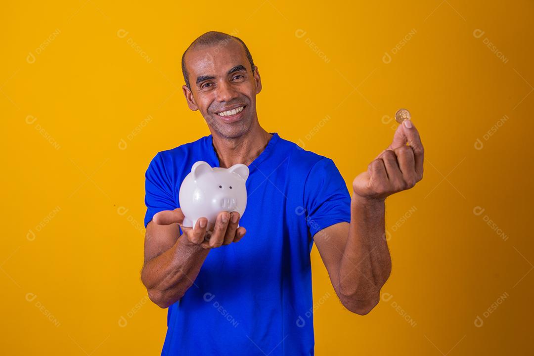 Homem afro segurando um cofrinho