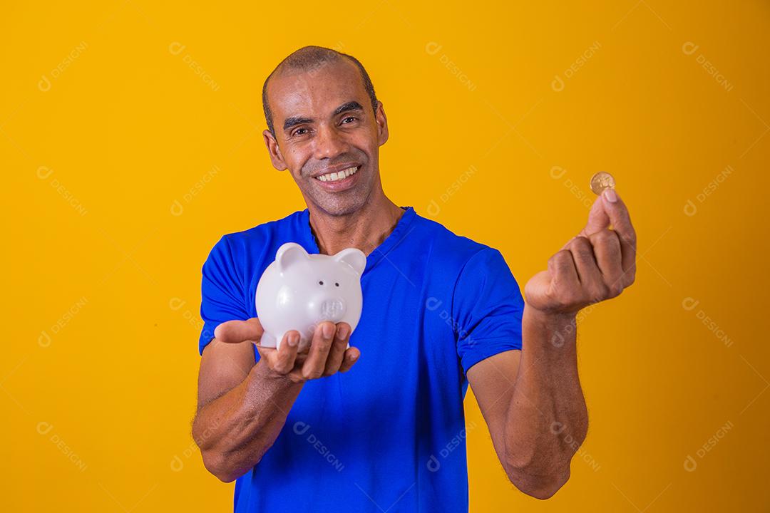 Homem afro segurando um cofrinho