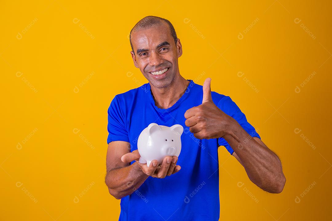 Homem afro segurando um cofrinho