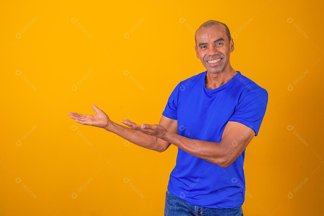 Oferta legal. Homem afro alegre apontando para no fundo amarelo do estúdio,