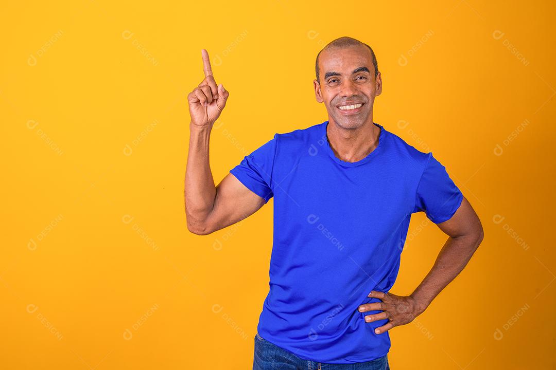 Oferta legal. Homem afro alegre apontando para no fundo amarelo do estúdio,