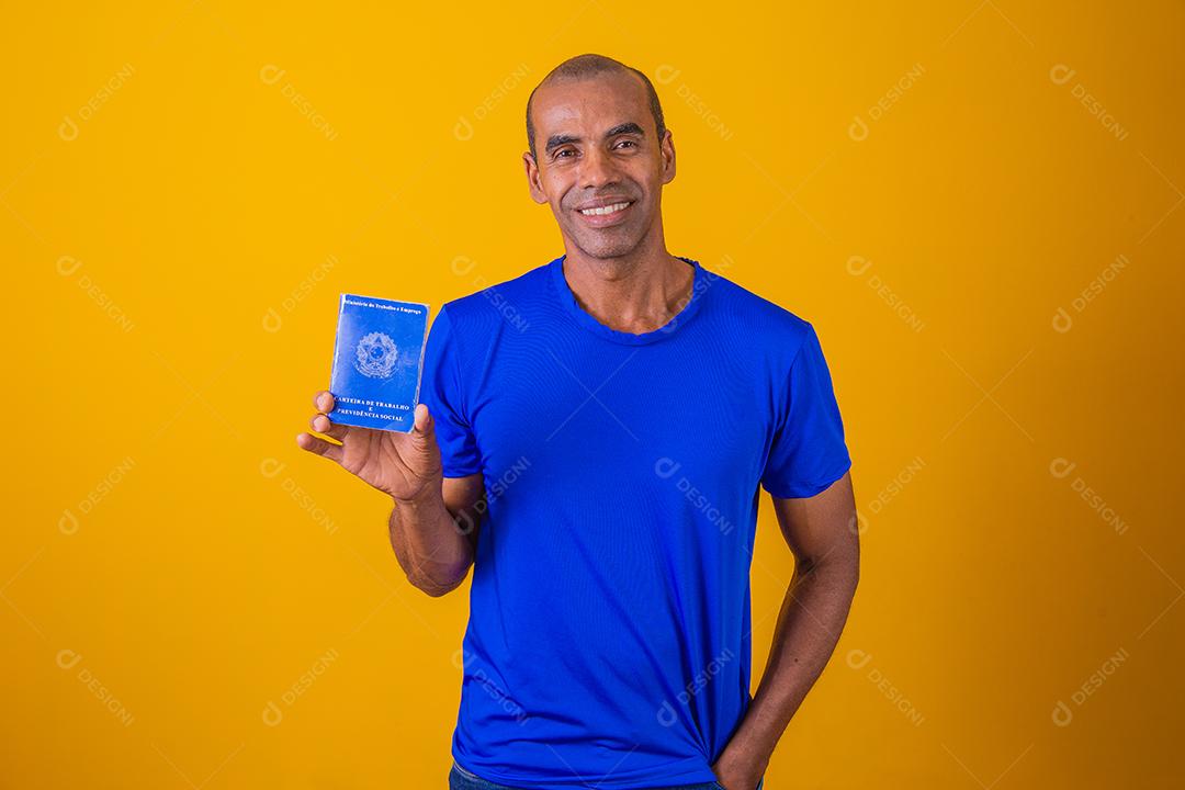 Homem brasileiro com trabalho documental e segurança social, (Carteira de Trabalho e Previdência Social) em fundo amarelo