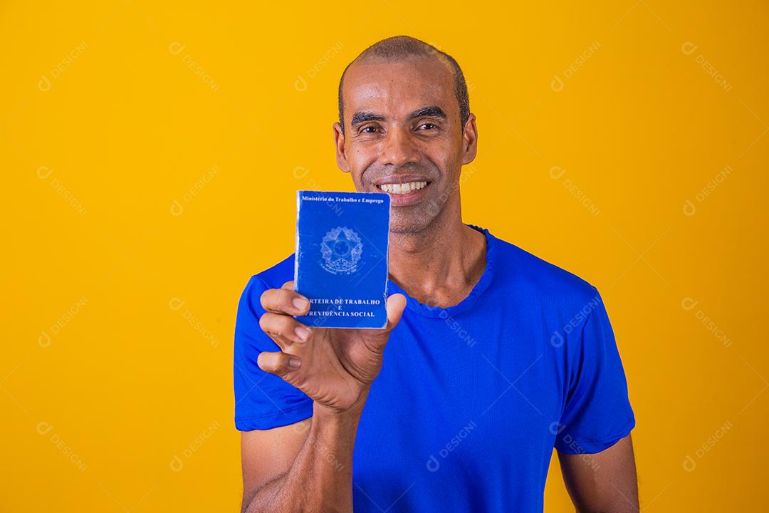 Homem brasileiro com trabalho documental e segurança social, (Carteira de Trabalho e Previdência Social) em fundo amarelo